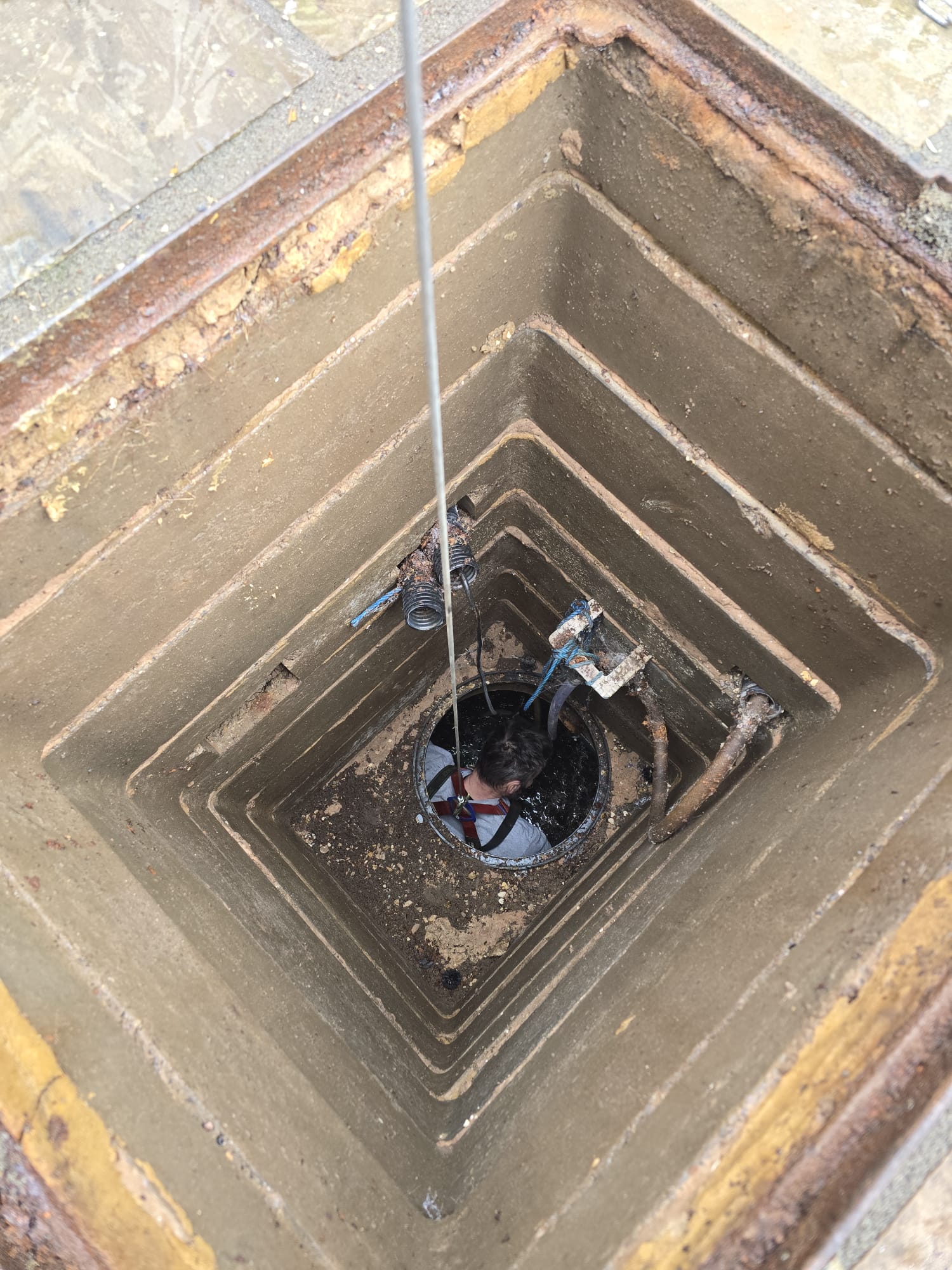 Engineer entering deep manhole chamber