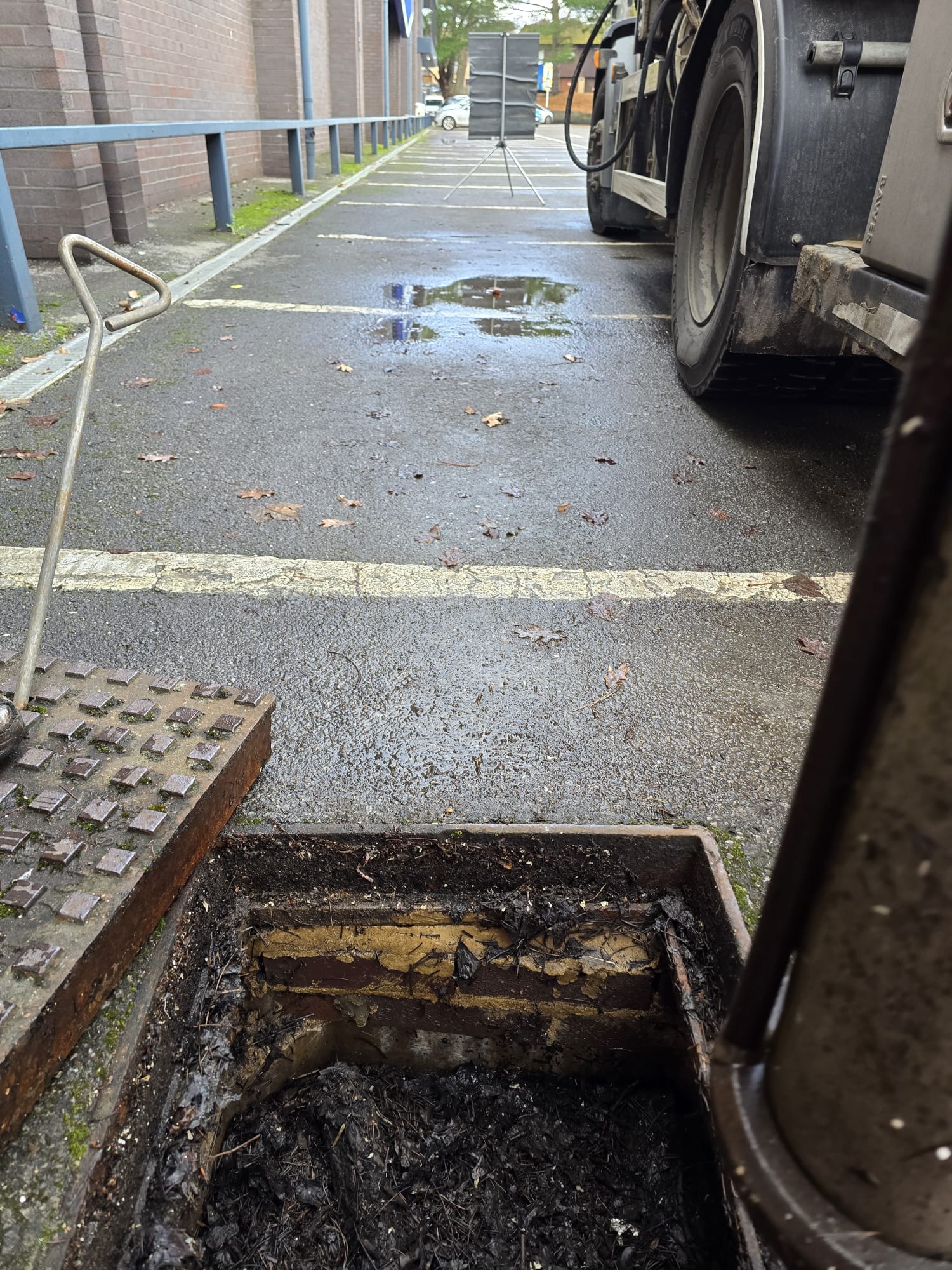 Open catchpit chamber beside parked tanker